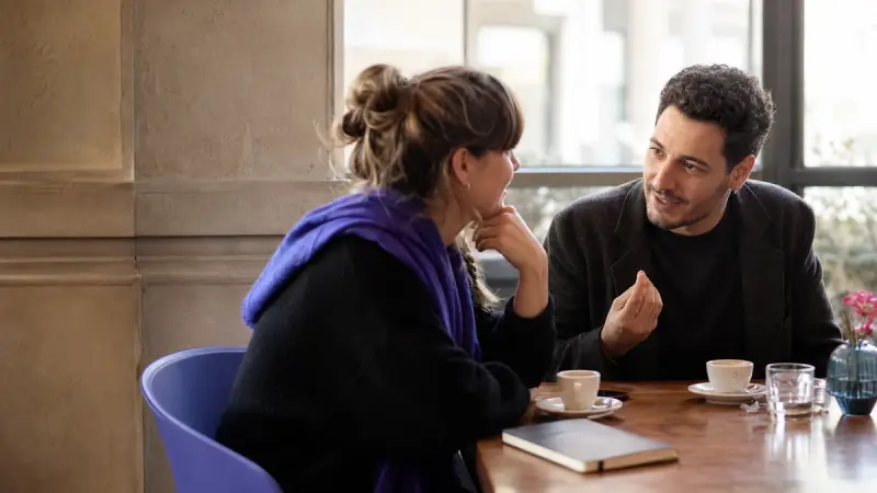 An Italian learner receiving a natural response during a neighborhood coffee chat