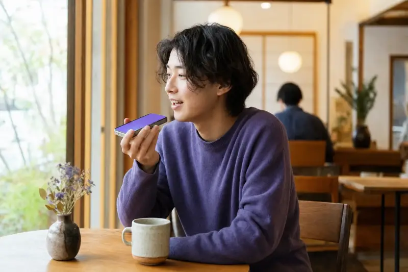 Young man sending a Japanese voice message at a cafe